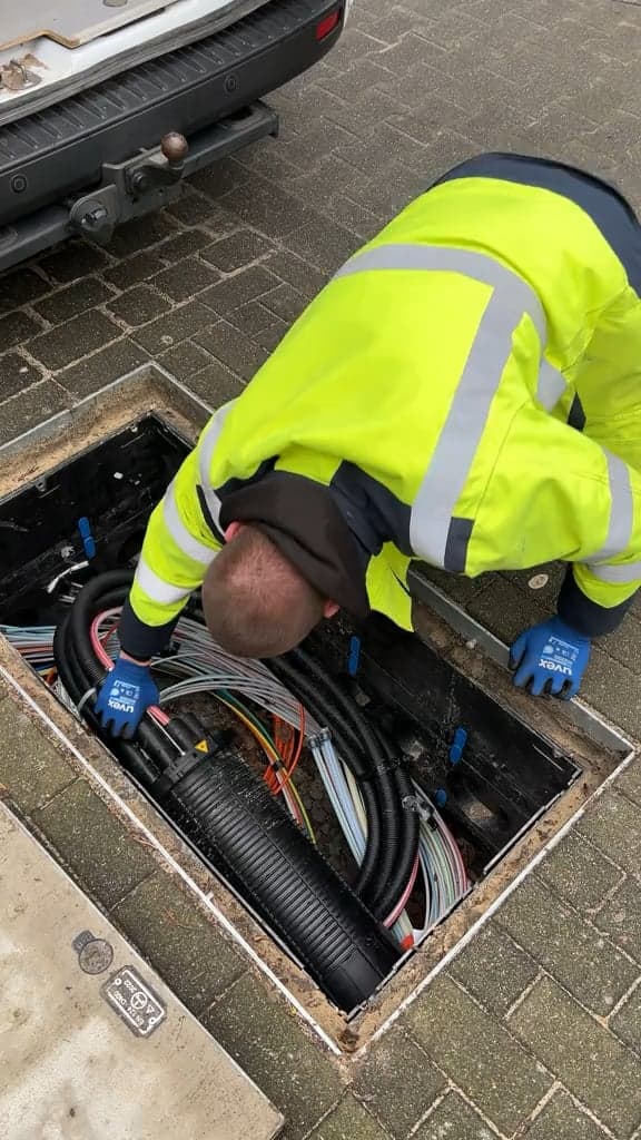Technician working fiber in an open handhole